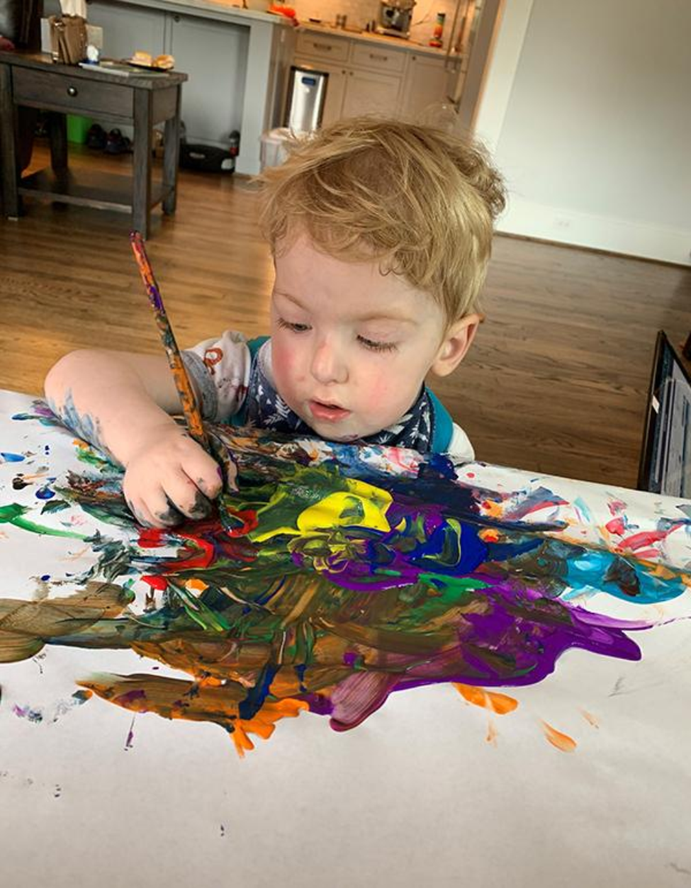 A photo of Levi Hoot painting while seated at the dining table. Photo credit: Nathan Hoot, MD. A photo of Levi Hoot painting while seated at the dining table. Photo credit: Nathan Hoot, MD.